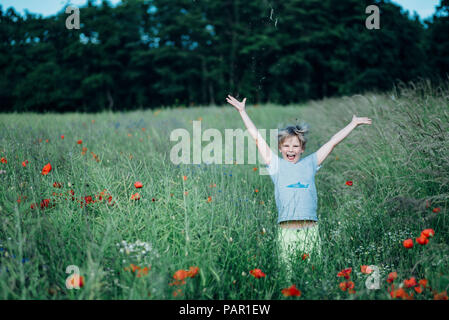 Portrait of happy boy dans champ de coquelicots Banque D'Images