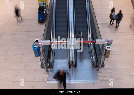 Une longue exposition photo de deux escaliers mécaniques au terminal de l'aéroport Rome lounge avec des membres du public zipping passé allant à et de leurs vols Banque D'Images