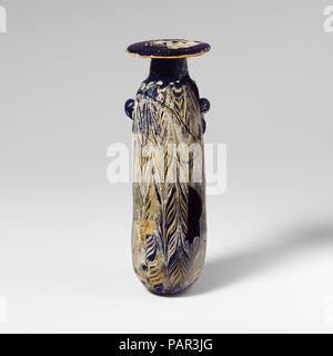 Alabastron en verre (flacon de parfum). Culture : le grec, l'Est de la Méditerranée ou l'italien. Dimensions : H. : 5 5/8 in. (14,3 cm). Date : mi-4e-début du 3e siècle avant J.-C.. Bleu cobalt translucide, avec poignées de même couleur ; sentiers en jaune opaque et blanc opaque. Horizontal large jante-disque, légèrement incliné vers l'extérieur, cylindrique, l'expansion du cou vers le bas ; l'épaule ; arrondi étroit corps cylindrique rectiligne, avec légère conicité convexe ; bas ; au-dessous de l'épaule, deux poignées anneau vertical, non percé à travers, avec de courtes a souligné, appliquée sur des sentiers de trail. Un bel itinéraire jaune attaché à Banque D'Images