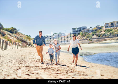 L'Australie, Adélaïde, Onkaparinga River, famille heureuse d'exécution sur la plage ensemble Banque D'Images