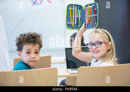Portrait d'écolier et d'écolière avec ordinateur portable et étui à crayons en classe Banque D'Images