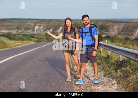 Le gars et la fille sont l'auto-stop le long de la route Banque D'Images