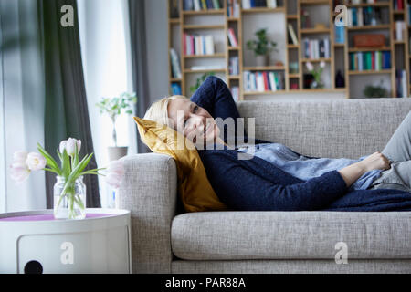 Woman relaxing at home, lying on couch Banque D'Images