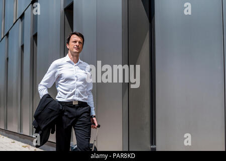 Businessman with rolling suitcase marcher dans la ville Banque D'Images