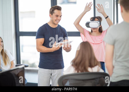 Avec l'enseignant étudiant tablette portant lunettes VR en classe Banque D'Images