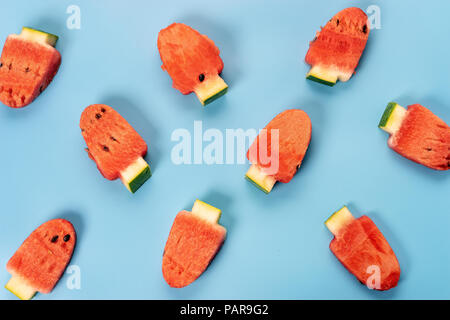 Mise à plat des tranches de melon mûr et juteux en forme de popsicle sur fond bleu Banque D'Images