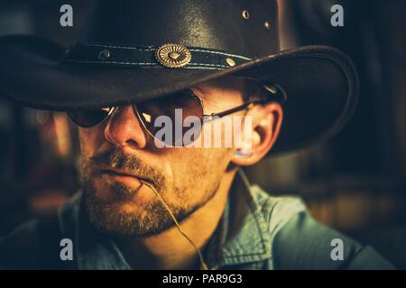 Portrait of Cowboy dans son 30s avec l'herbe de la paille dans sa bouche.. Portrait Photo. Banque D'Images