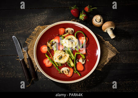 Salade aux asperges vertes, champignons, fromage de chèvre, fraises et noix de pin, grillées Banque D'Images