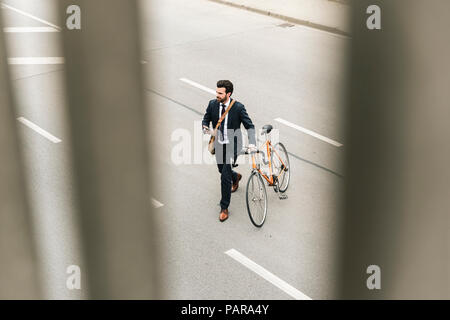 Businessman with location et de téléphones cellulaires en marchant dans la rue Banque D'Images