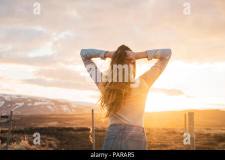 L'Islande, jeune femme avec les mains dans les cheveux au coucher du soleil Banque D'Images