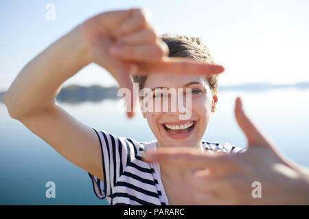 Portrait of laughing woman in front of lake l'élaboration de cadre avec ses doigts Banque D'Images