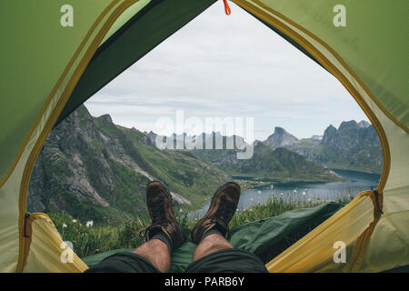 La Norvège, les îles Lofoten, Moskenesoy, les pieds de l'homme, couché dans une tente sur Kjerkefjord Banque D'Images