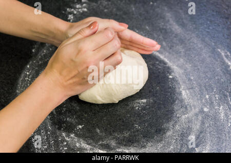 Femme préparant la pâte à pizza sur la table en granit noir Banque D'Images