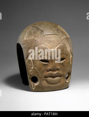 La chape. Culture : Olmèque. Dimensions : H. 7 1/2 x 5 7/8 x D. W. dans 6. (19.1 x 14.9 x 15.2 cm). Date : 10ème-4ème siècle avant JC. Un premier exemple d'une 'joug' Mésoaméricain Préclassique (ainsi nommé pour sa similitude formelle aux chapes agricoles modernes), cette sculpture en pierre sereine contient un portrait. Le visage humain a été formé en faible relief et contient des lèvres pleines, un large nez, sculptés dans les yeux à sourcils incisés, et les oreilles. Les lobes sont dépeints comme étirés et grands sondages pourrait avoir été utilisé pour fixer des ornements d'oreille au visage. La racine est coupée de la surface de la pierre, peut-être à c Banque D'Images
