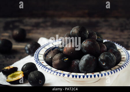 Les prunes mûres et fraîches sur une plaque sur un fond de bois, macro, selective focus. Banque D'Images
