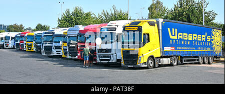 Camion camion poids lourds étrangers et des bandes-annonces à la nuit sur un parking d'autoroute Thurrock deux services cabine conducteur parlant plat antenne satellite sur camions et camions UK Banque D'Images