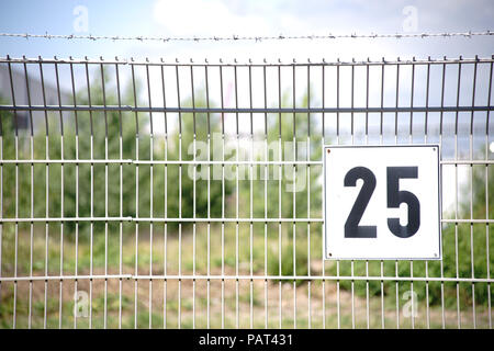 Le détail d'une clôture en treillis avec le numéro d'une parcelle clôturée avec du fil de fer barbelé. Banque D'Images