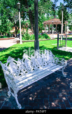 Une ancienne fer ornemental travail défilement banc de parc avec assise en bois dans la région de plaza près de gazebo dans old town Albuquerque NM Banque D'Images
