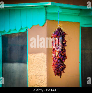 Un traditionnel red chili rista se bloque à partir de l'avant-toit de couleur turquoise boîte adobe maison dans la vieille ville d'Albuquerque, NM Banque D'Images