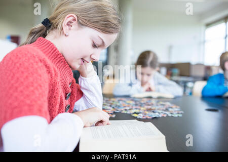 Lycéenne lecture livre sur le tableau à l'école de la salle de pause Banque D'Images