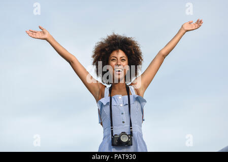 Portrait of happy young woman with camera against sky Banque D'Images