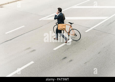 Businessman with bicycle on cell phone marche dans la rue Banque D'Images