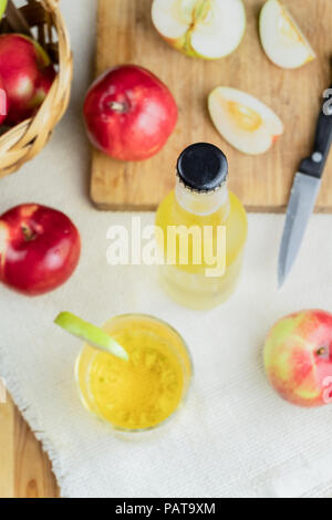 Vue de dessus sur bouteille cidre et pommes mûres table rustique en bois. Verre et bouteille de cidre fait maison et pommes biologiques cultivés localement, en plongée des Banque D'Images