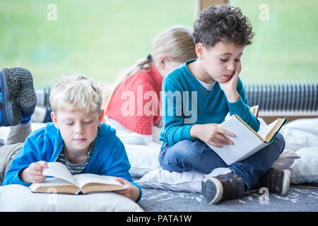 Les élèves à lire des livres sur le sol dans la salle de pause de l'école Banque D'Images