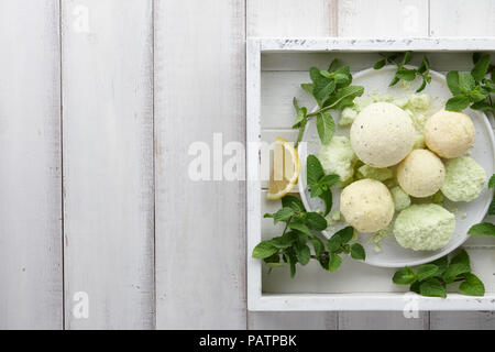 Bombes de bain menthe à la main avec des herbes fraîches dans le bac blanc Banque D'Images