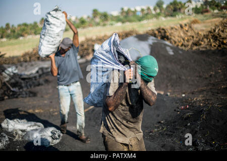 Palestiniens vu porter des sacs de charbon de bois après leur achat à l'installation. L'extraction de charbon de sable à l'Al Habbash usine de production, le plus grand producteur de charbon dans la bande de Gaza. Il est habituellement utilisé par les Palestiniens pour des raisons pratiques, telles que la cuisine et le chauffage. Un kilo est vendu pour $ 1,50 2,00 $ sur place et sur le marché. Banque D'Images