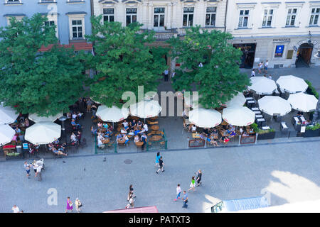 Vue sur le toit à la recherche vers le bas sur les touristes profiter de vos repas et boissons sous le soleil Parasols, Main Square, Cracovie, Pologne, Europe. Banque D'Images