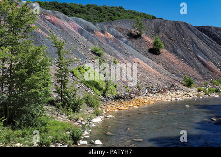 Déchets de résidus de mine de charbon le tas de déblais à côté d'un ruisseau à l'orange rochers montrant les dommages environnementaux de la pollution toxique et le drainage minier acide. Banque D'Images