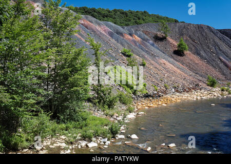 Déchets de résidus de mine de charbon le tas de déblais à côté d'un ruisseau à l'orange rochers montrant les dommages environnementaux de la pollution toxique et le drainage minier acide. Banque D'Images