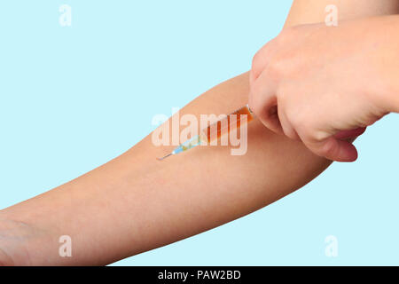 Close-up of hand, donnant au patient la vaccination à l'aide d'une seringue avec Brown de la drogue. Le matériel d'injection stérile dans le bras sur fond bleu clair, toxicomane. Banque D'Images