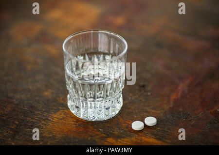 Verre d'eau pure et quelques comprimés ronds blancs sur la table en bois. Comprimés médicaux Banque D'Images
