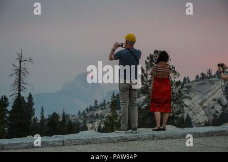 Yosemite National Park, California, USA. 24 juillet, 2018. Le Mardi, Juillet 24, 2018.Yosemite National Park les visiteurs de prendre des photos à Olmsted Point le long de Tioga Pass Road et l'autoroute 120 dans le haut pays du parc. Demi Dôme est vu dans l'arrière-plan à travers la fumée des incendies Ferguson. Le feu brûle près de l'entrée du parc El Portal. Credit : Tracy Barbutes/ZUMA/Alamy Fil Live News Banque D'Images