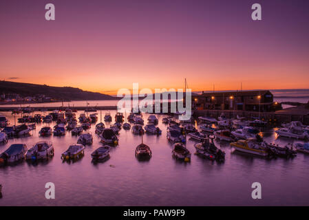 Lyme Regis, dans le Dorset, UK. 25 juillet 2018. Météo France : Golden sunrise à Lyme Regis. Les bateaux dans le port sont découpé sur la lumière dorée du petit matin ciel sur une autre journée chaude et ensoleillée dans la station balnéaire ville de Lyme Regis. Credit : Celia McMahon/Alamy Live News. Banque D'Images