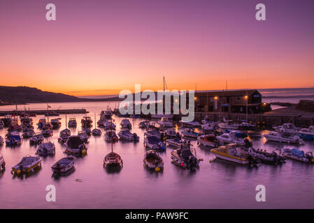 Lyme Regis, dans le Dorset, UK. 25 juillet 2018. Météo France : Golden sunrise à Lyme Regis. Les bateaux dans le port sont découpé sur la lumière dorée du petit matin ciel sur une autre journée chaude et ensoleillée dans la station balnéaire ville de Lyme Regis. Credit : Celia McMahon/Alamy Live News. Banque D'Images