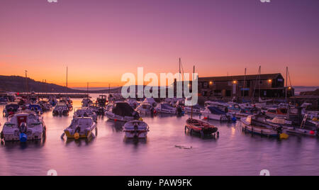 Lyme Regis, dans le Dorset, UK. 25 juillet 2018. Météo France : Golden sunrise à Lyme Regis. Les bateaux dans le port sont découpé sur la lumière dorée du petit matin ciel sur une autre journée chaude et ensoleillée dans la station balnéaire ville de Lyme Regis. Credit : Celia McMahon/Alamy Live News. Banque D'Images