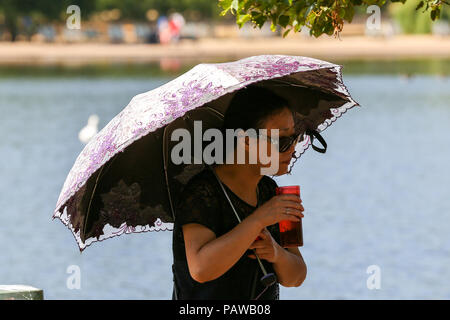 Hyde Park. Londres. UK 25 Juillet 2018 - une femme à l'abri de soleil fort sous un parapluie dans Hyde Park sur une journée très chaude et humide dans la capitale. D'après le Met Office la température de Londres et du sud-est est susceptible d'atteindre 35 degrés celsius le jeudi. Credit : Dinendra Haria/Alamy Live News Banque D'Images