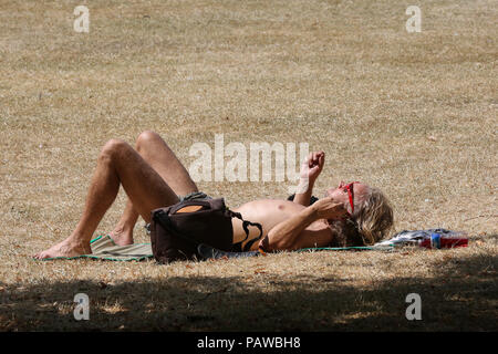 Hyde Park. Londres. Royaume-uni 25 juin 2018 - Un homme de soleil sur l'herbe desséchée brûlées dans Hyde Park sur une journée très chaude et humide dans la capitale. D'après le Met Office la température de Londres et du sud-est est susceptible d'atteindre 35 degrés celsius le jeudi. Credit : Dinendra Haria/Alamy Live News Banque D'Images