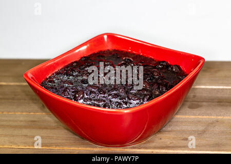 Bol rouge rempli de soupe de haricots noirs prêts à manger sur la table de cuisine Banque D'Images