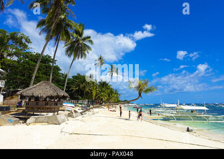 Alona Beach, Bohol - Philippines - une cabane de plage donne sur la mer turquoise et d'innombrables bateaux d'excursion. Banque D'Images