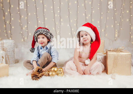 Portrait des enfants de race blanche blanc frères amis fêter Noël ou Nouvel An. Peu cute adorable girl and boy wearing santa claus hats tr Banque D'Images