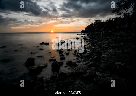 Une longue exposition photo de coucher du soleil orange sur Rocky Island Beach - Cebu, Philippines Banque D'Images