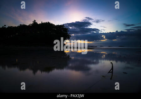 Une ancre d'un bateau de pêche se trouve dans le calme de l'eau de mer à marée basse avec un coucher du soleil - réflexion l'île de Malapascua, Cebu - Philippines Banque D'Images