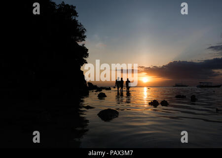 3 jeunes hommes à marcher le long du bord de l'eau sur la plage de l'île magnifique aux Philippines. Banque D'Images