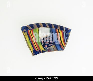 Mosaïque à rayures en forme de lentilles en verre lave fragment. Culture : Roman. Dimensions : 1 × 1 × 1/16 9/16 1/8 in. (2,6 × 4 × 0,3 cm) diamètre estimé : 3 9/16 in. (9 cm). Date : fin du 1er siècle avant J.-C.-début 1er siècle de notre ère. Bleu de cobalt, translucide lumière apparaissant partiellement bleu ou vert, jaune opaque, blanc, rouge, et incolore. Debout, bord arrondi ; peu profonde, une courbe convexe côté. Striped modèle mosaïque formée de deux longueurs de canne composite carré et les articles placés côte à côte en rangées parallèles : une canne en vert, bleu, rouge et jaune disposés dans un miroir sur chaque côté de Banque D'Images