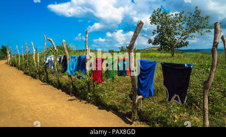 Des vêtements colorés en train de sécher dehors sur une route de terre de l'île de Catanduanes, Philippines Banque D'Images