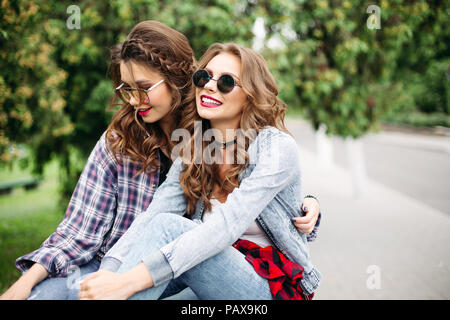 Portrait de jeunes filles avec de magnifiques cheveux blonds et brune dans le port de lunettes à la mode coiffures et vêtements décontractés cropped en gr Banque D'Images